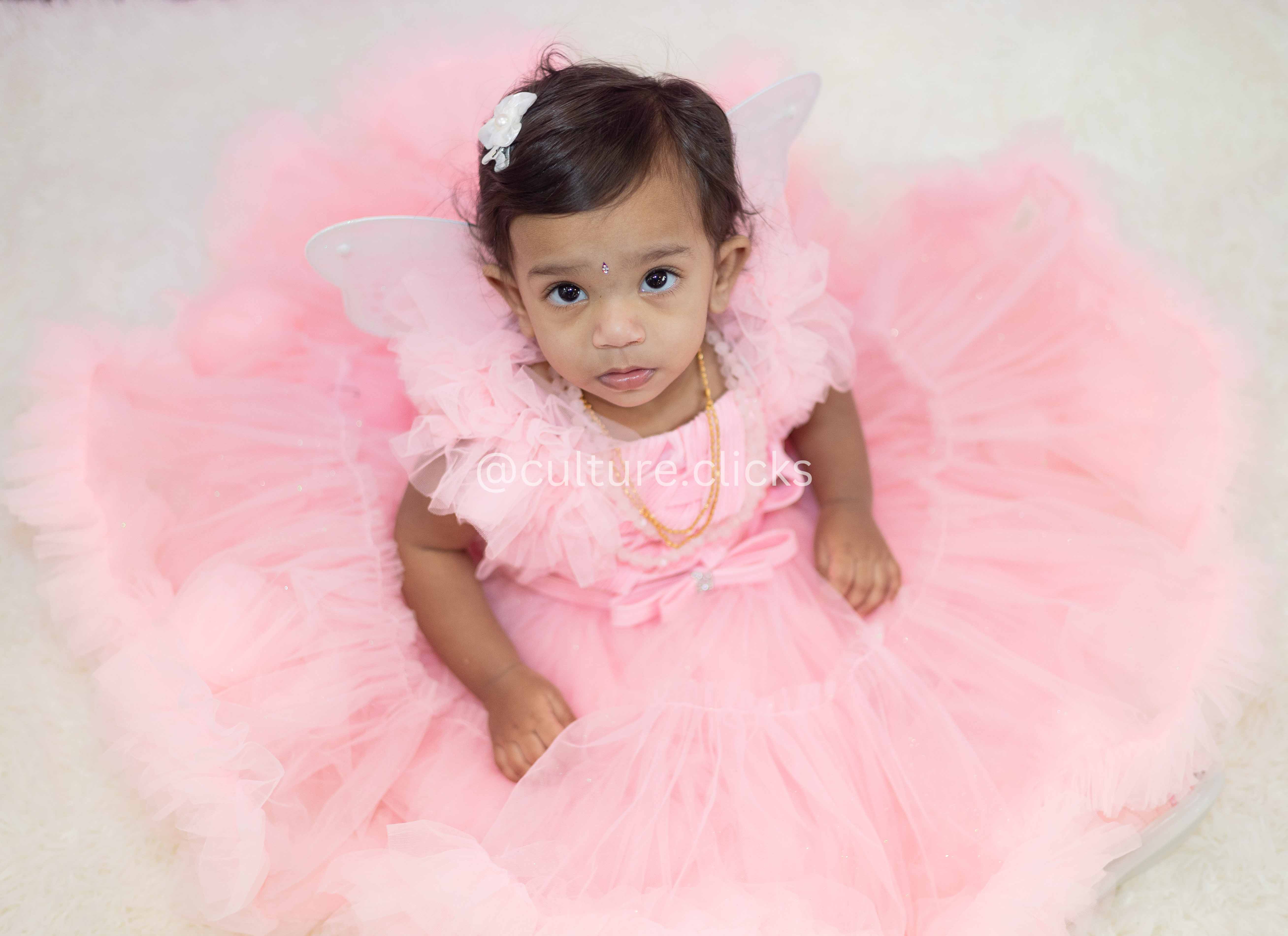 Beautiful flower like baby with pink fluffy dress and tulle skirt. sitting like a flower captured by cultureclicks photography with decorations done by cultureclicks