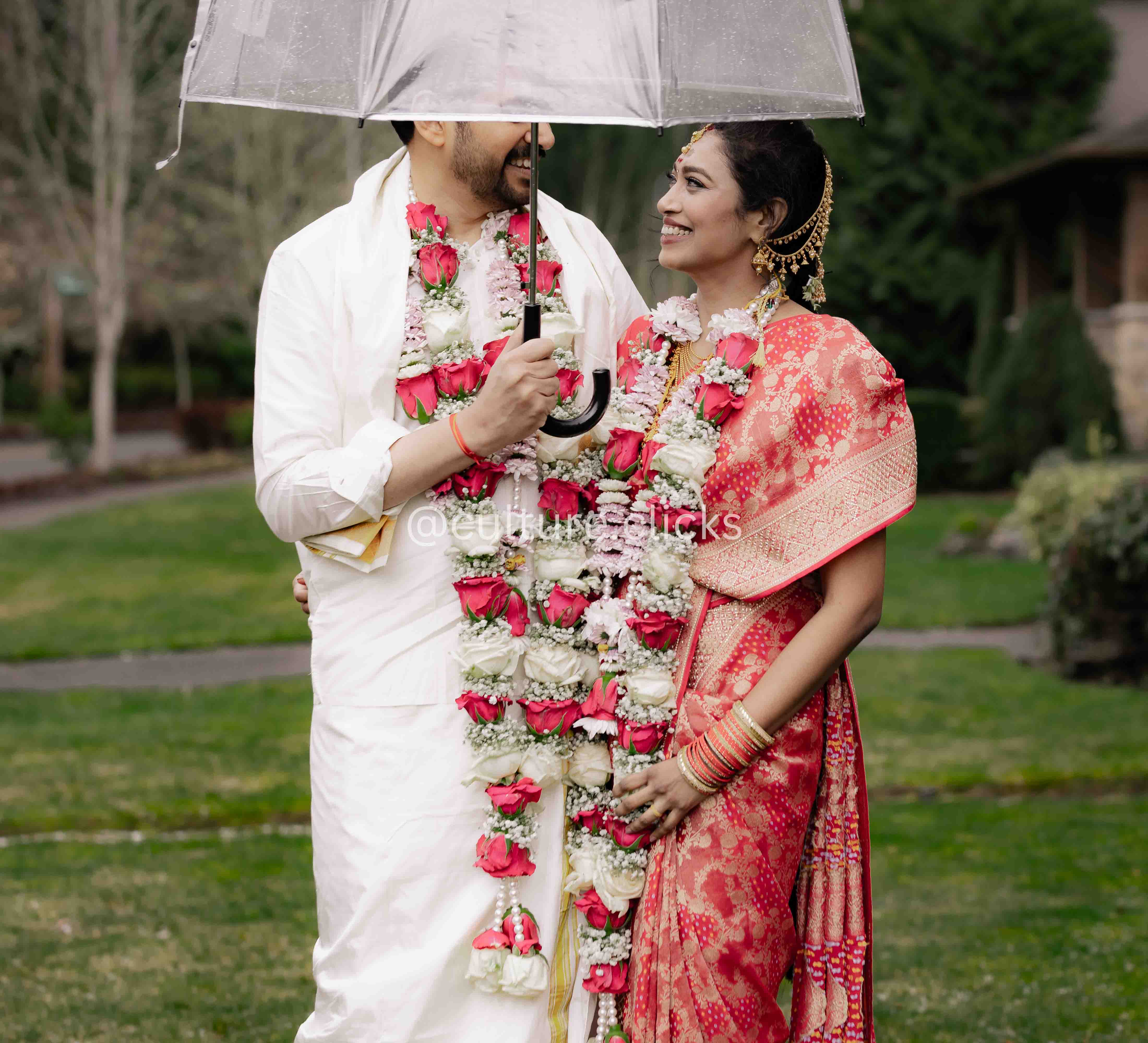 Groom holding his beautiful wife bride in rain with clear umberella photography captured by culture clicks photography by seattle indian wedding photographer
